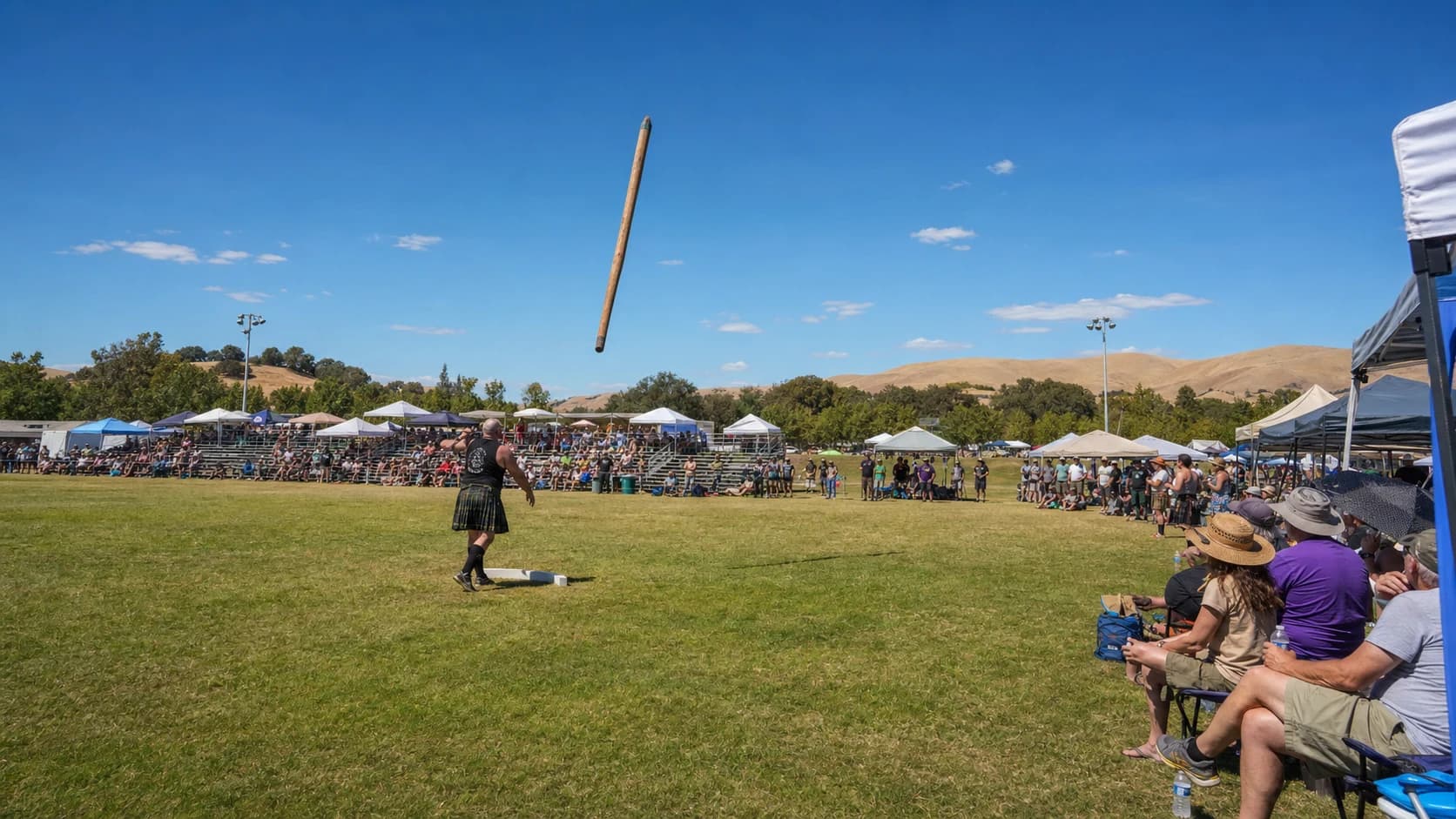 Caber competition and spectators beneath a hot blue sky at the Pleasanton fairgrounds