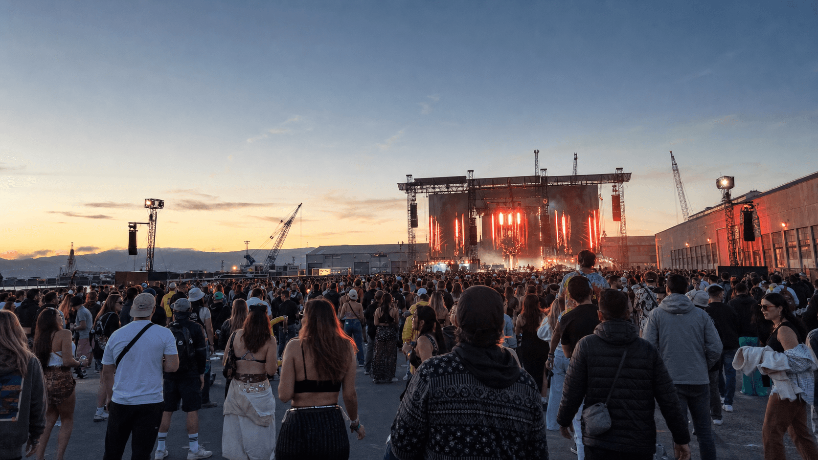 Portola festival crowd facing an outdoor stage at the industrial Pier 80 waterfront near sunset